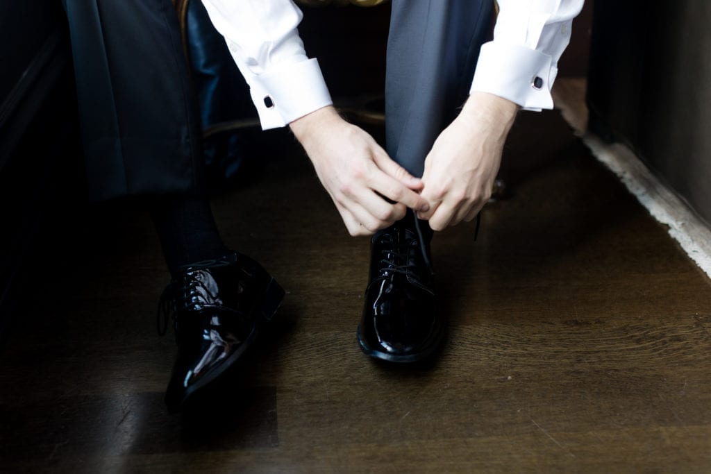 groom detail shots of tying shoes