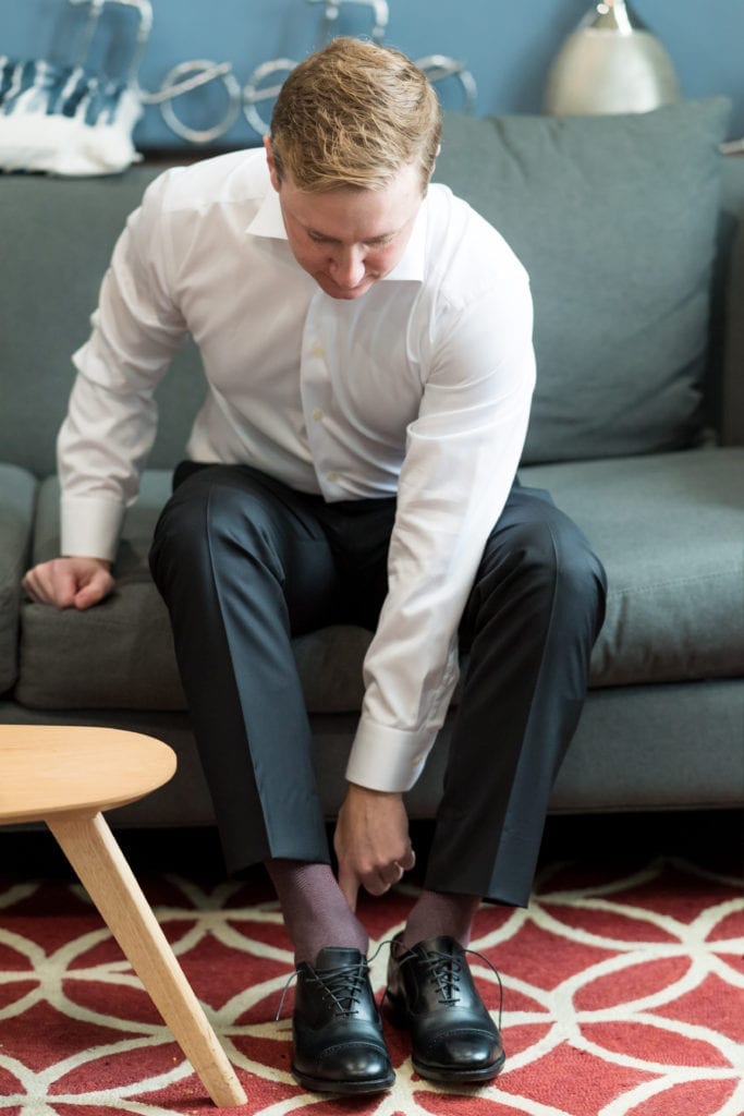 groom putting on his shoes for his wedding