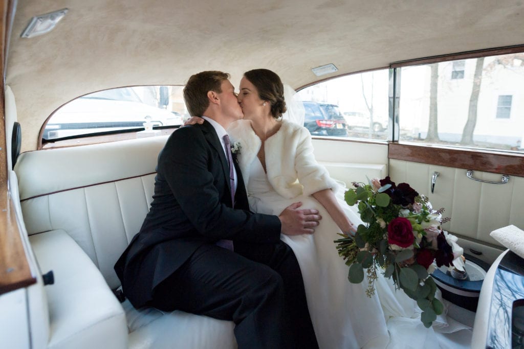  bride and groom in the car after the wedding sharing a kiss