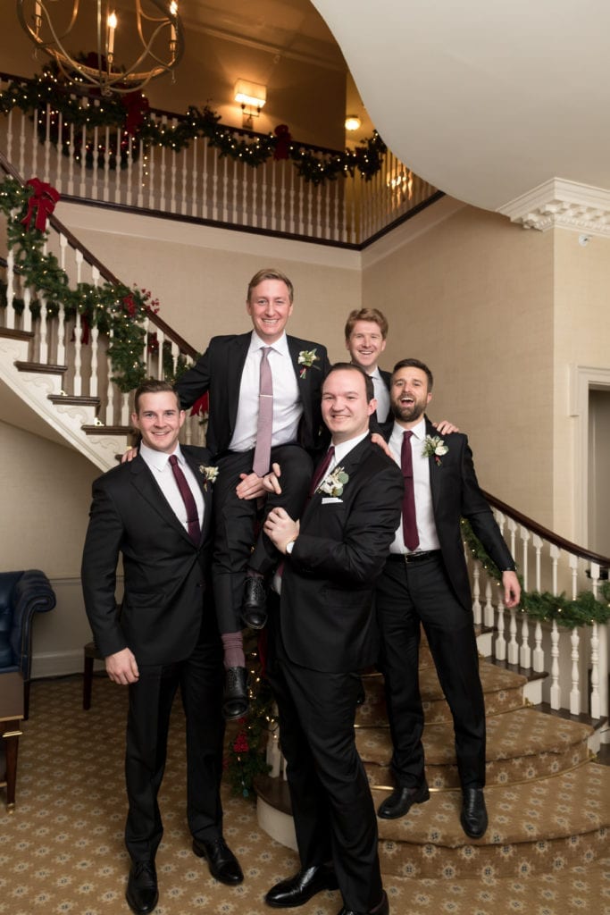 groomsmen picking up the groom