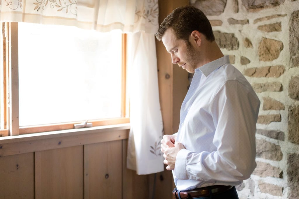 groom buttoning his shirt