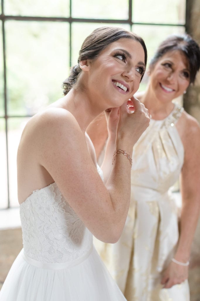 bride putting on her wedding jewelry