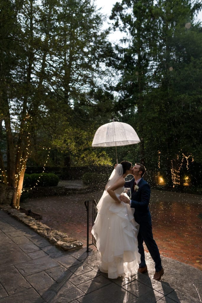 bride and groom kissing in the rain