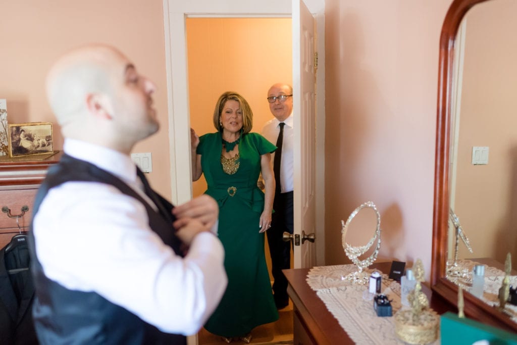 father and mother of the groom checking on him as he gets ready