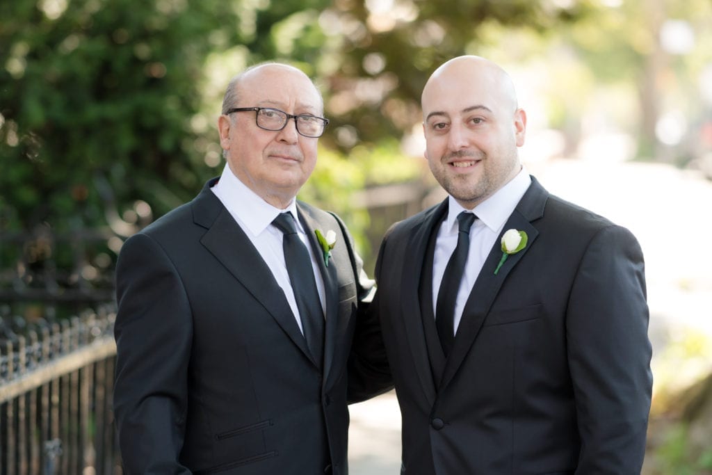 father of the groom and groom posing for photo 