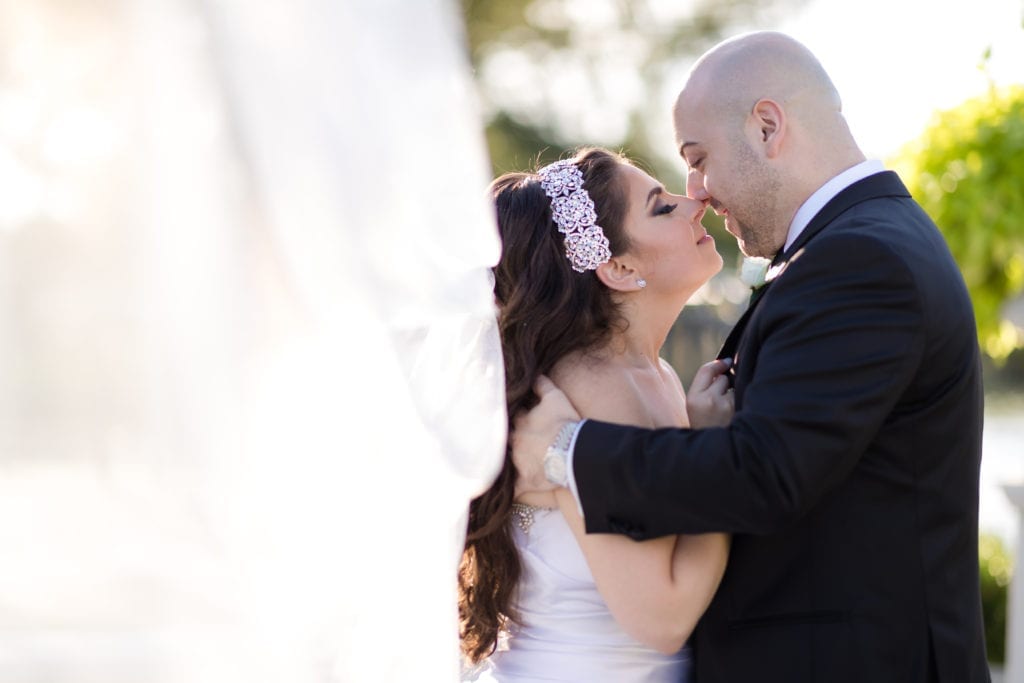 bride giving her groom a kiss with her veil blowing in the wind