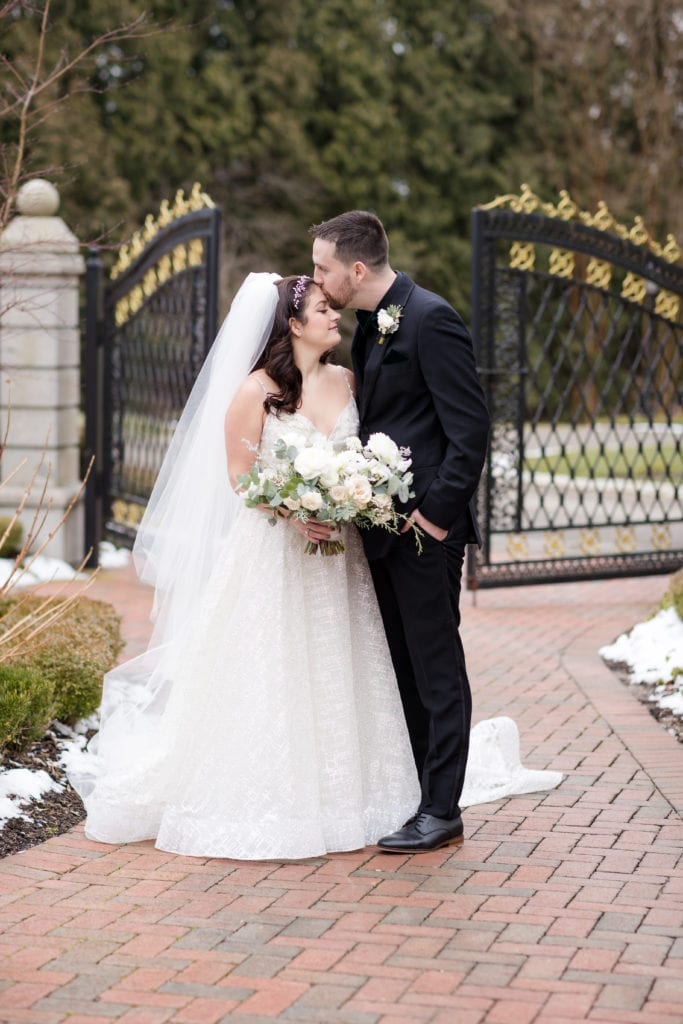 bride kissing his groom on her forehead 