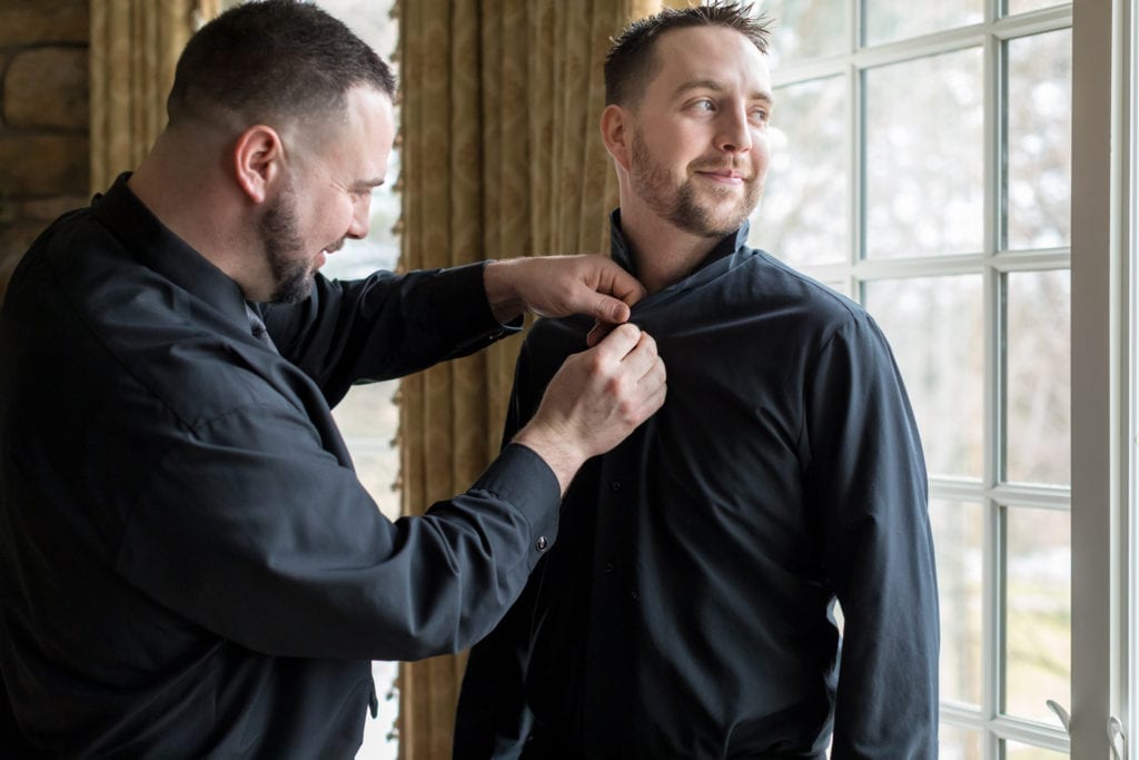 groomsmen helping groom get ready