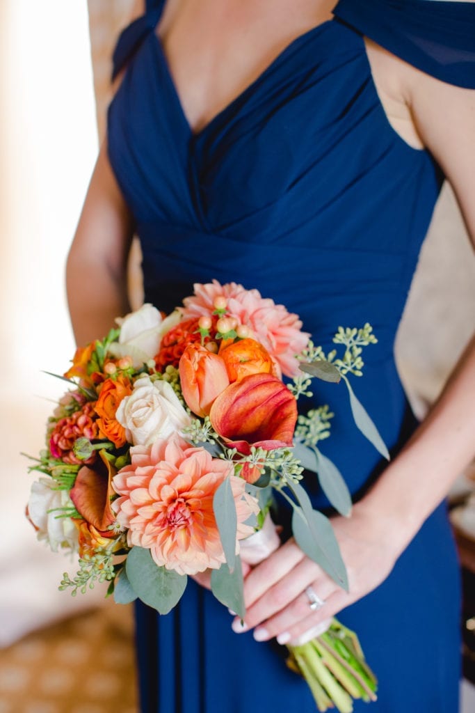 Navy cap sleeve bridesmaid dress, bright orange fall themed bouquet 