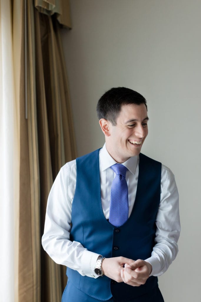 groom laughing while getting ready for wedding