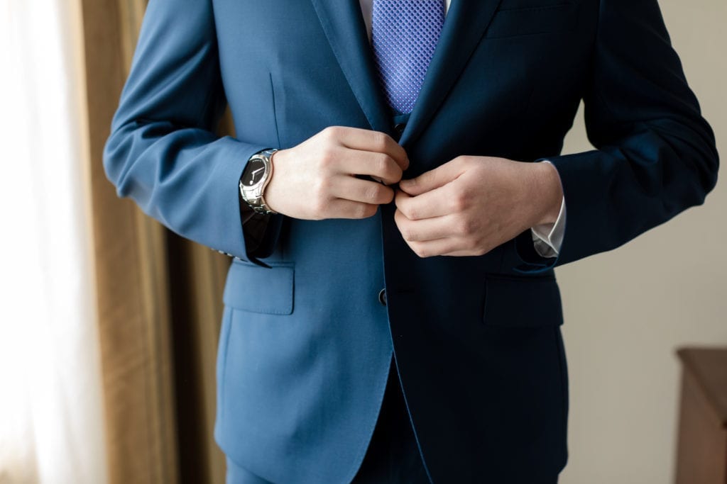 groom buttoning up his suit jacket