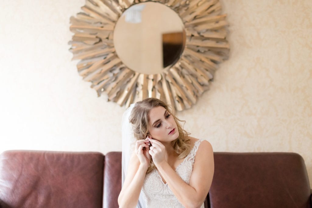 bride putting on her earrings; wedding jewelry