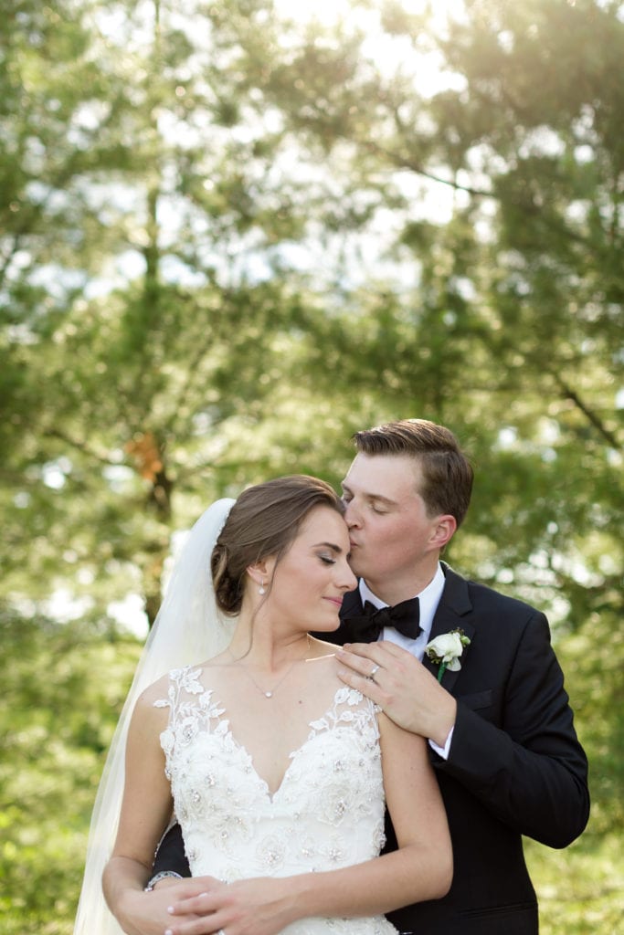 groom kissing brides forehead, springtime wedding