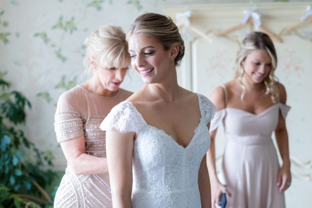 Monique Lhuillier wedding dress, mom helping daughter put on wedding dress