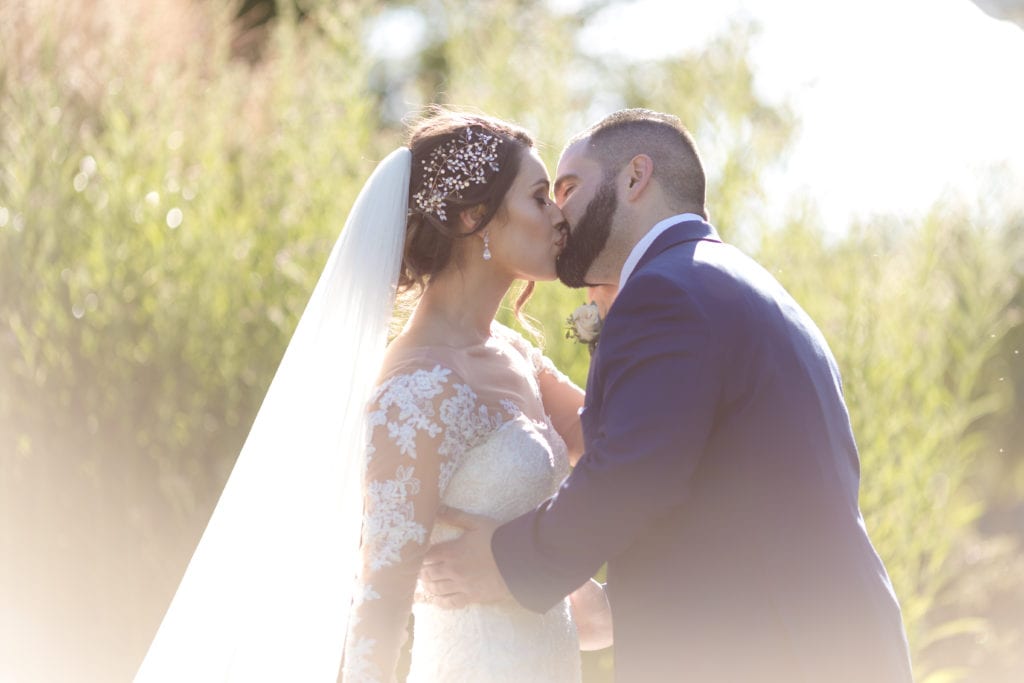 bride and groom kissing with sunlight shining on them