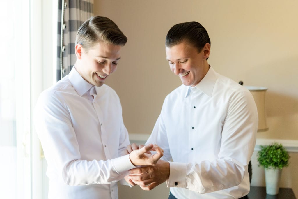 groom and groomsman getting dressed