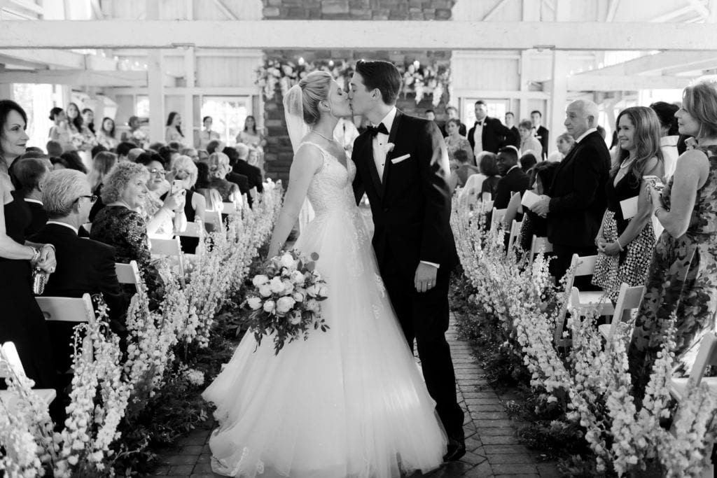 black and white photo of bride kissing at exiting their ceremony