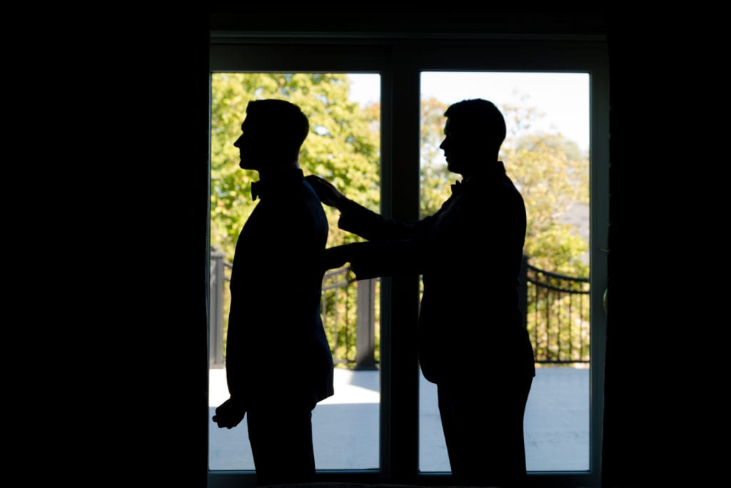 Best man helping groom get ready on wedding day