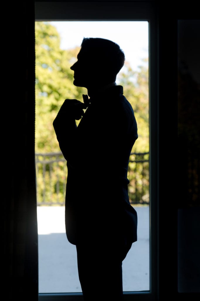 groom putting his bow tie on 