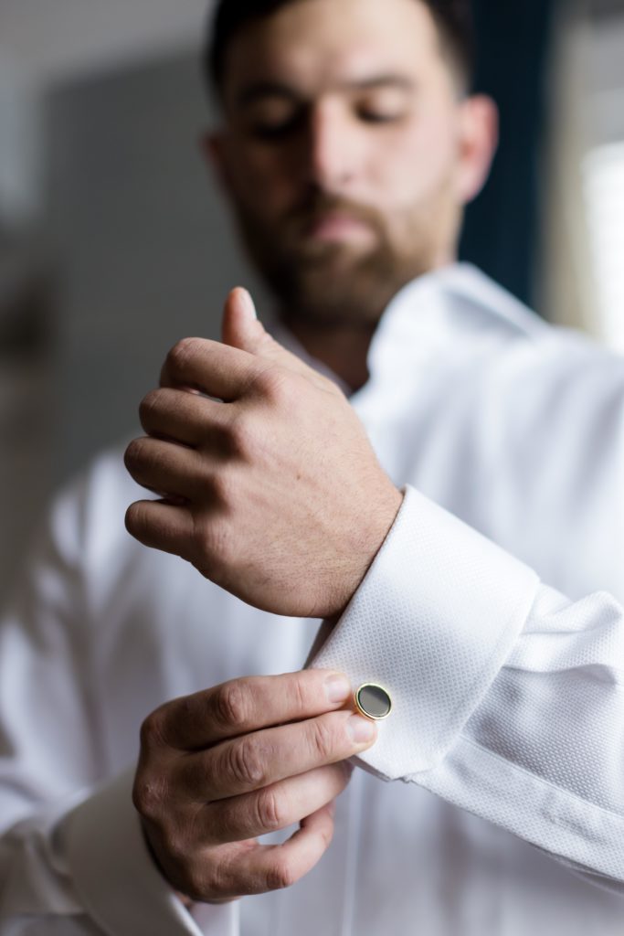 groom buttons up his shirt, groom's preparations