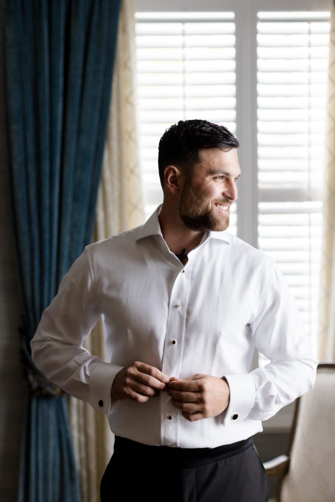 groom buttons up his shirt, groom's preparations