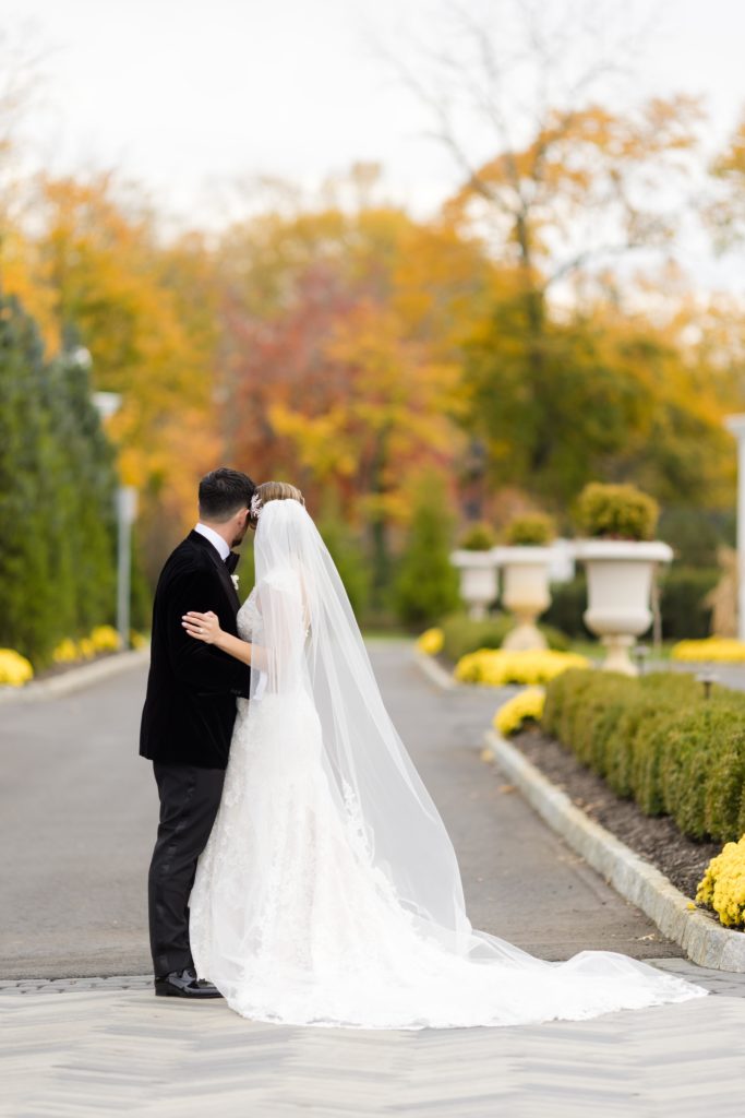 Bride and groom look away, wedding portraits, wedding portraits, Maggie Sottero Designs wedding gown, lace-edged veil, classic tux