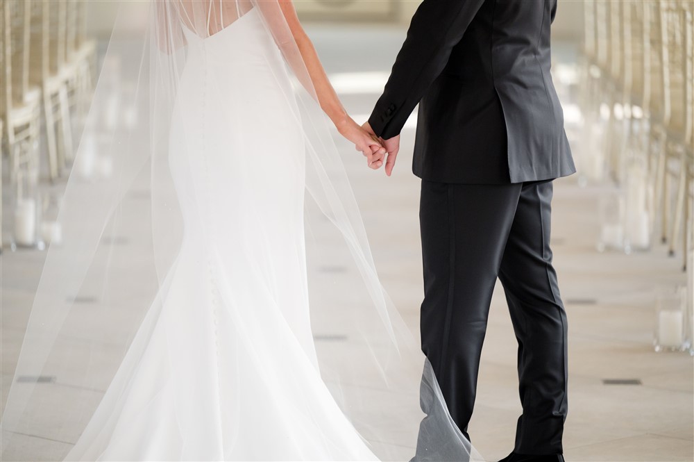 BRIDE AND GROOM HOLDING HANDS DOWN AISLE