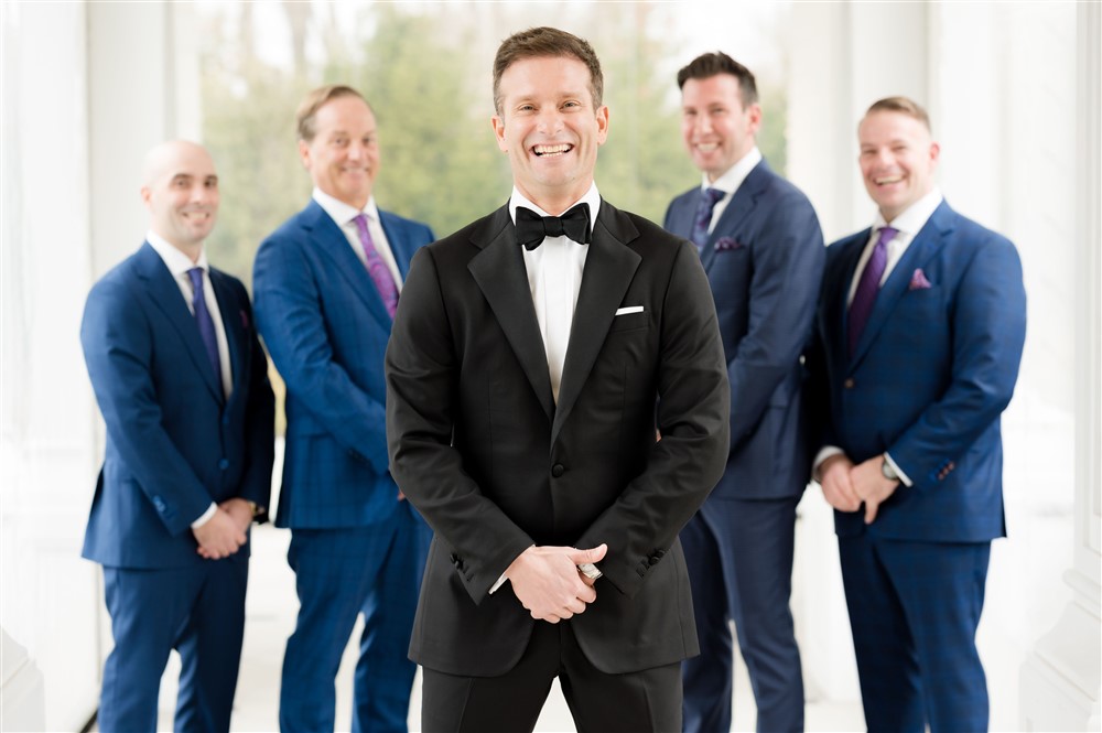 happy groom with his groomsmen in background