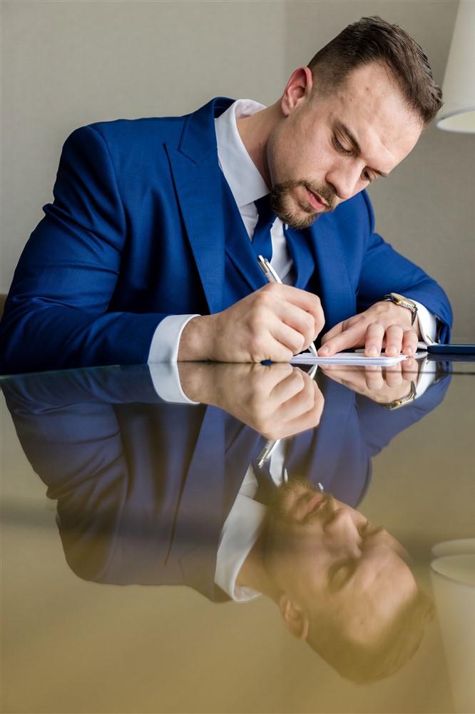 reflection photo of groom writing down vows