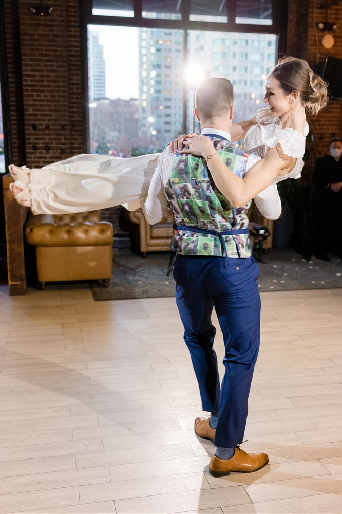 Groom wearing Mr. Robbie suits carrying bride on dancefloor