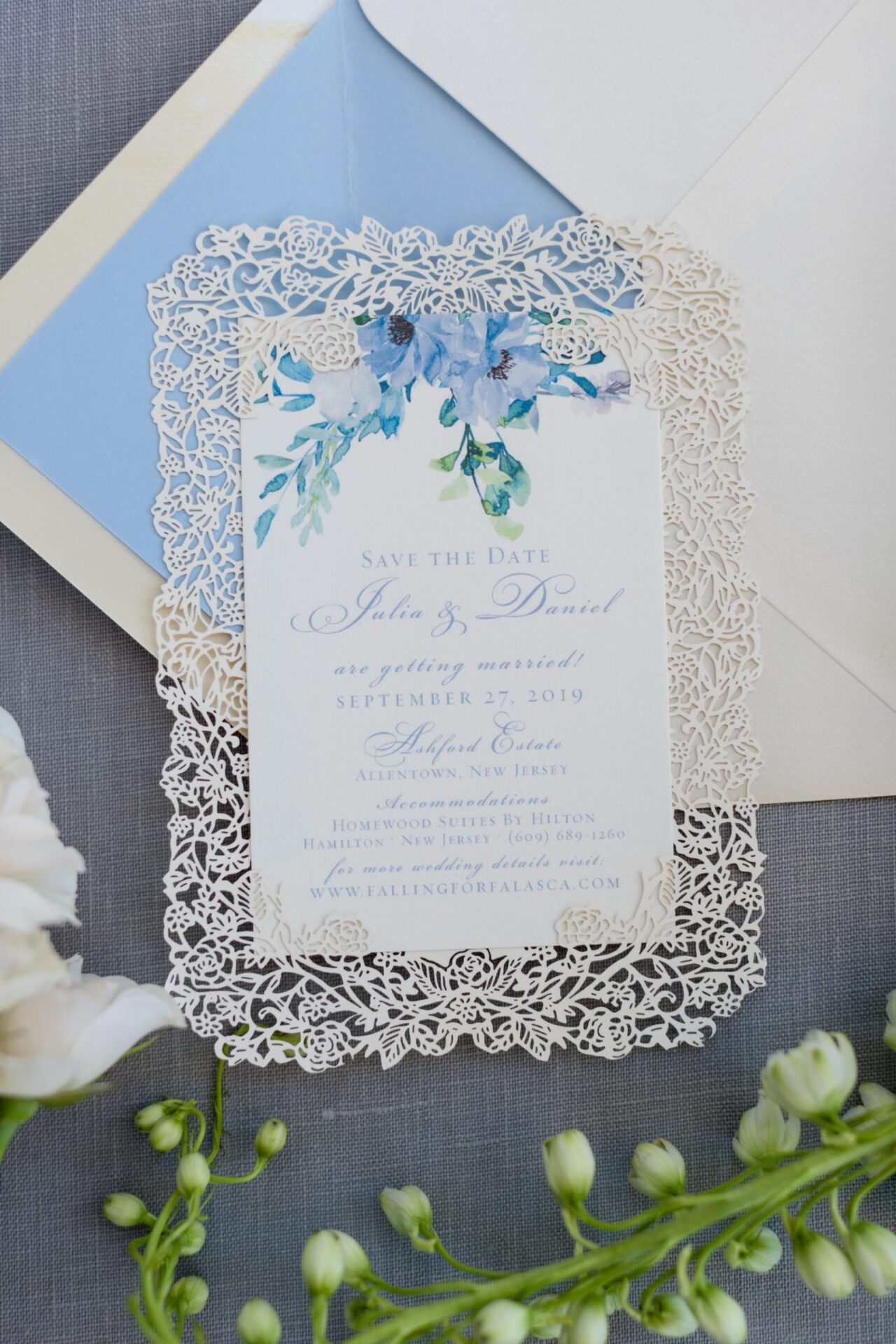 Laser-cut save the date with blue watercolor flowers on a blue envelope