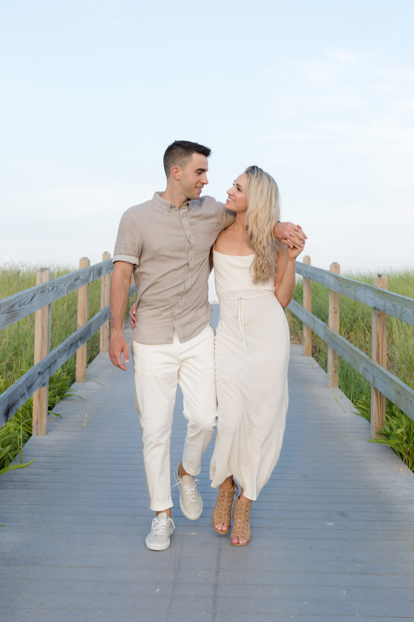 Couple walking arm in arm on a Spring Lake boardwalk through dune grass