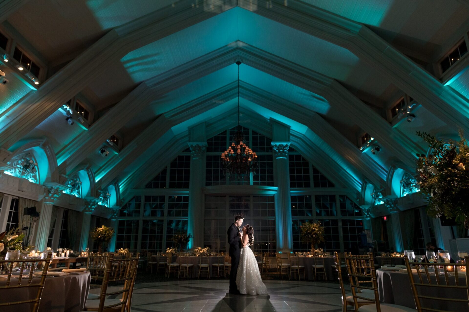 Couple embracing in the Ashford Estate ballroom lit in teal